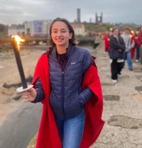 Young person holds a lighted torch outside